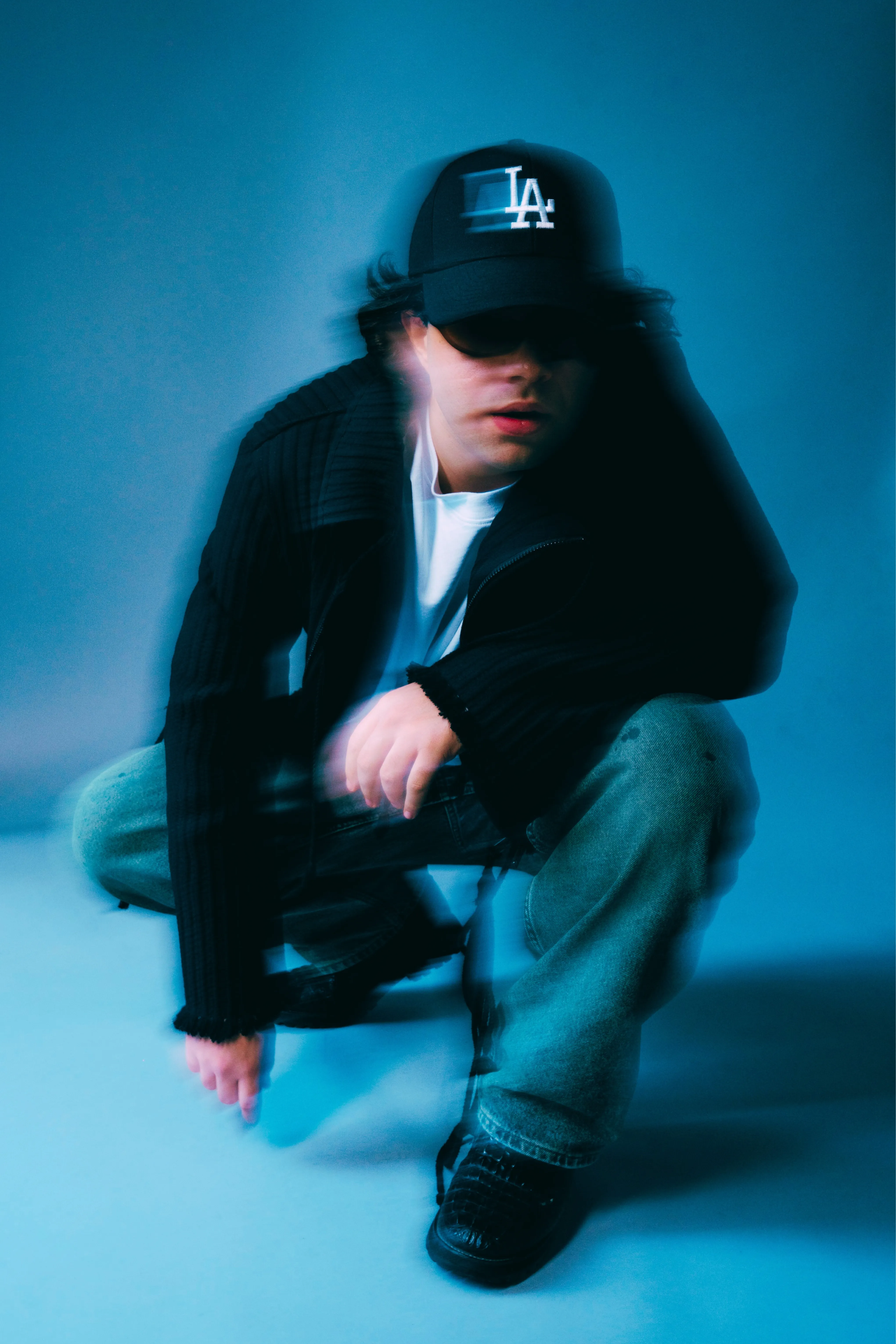 AMANN crouching, motion-blurred, against a blue backdrop
