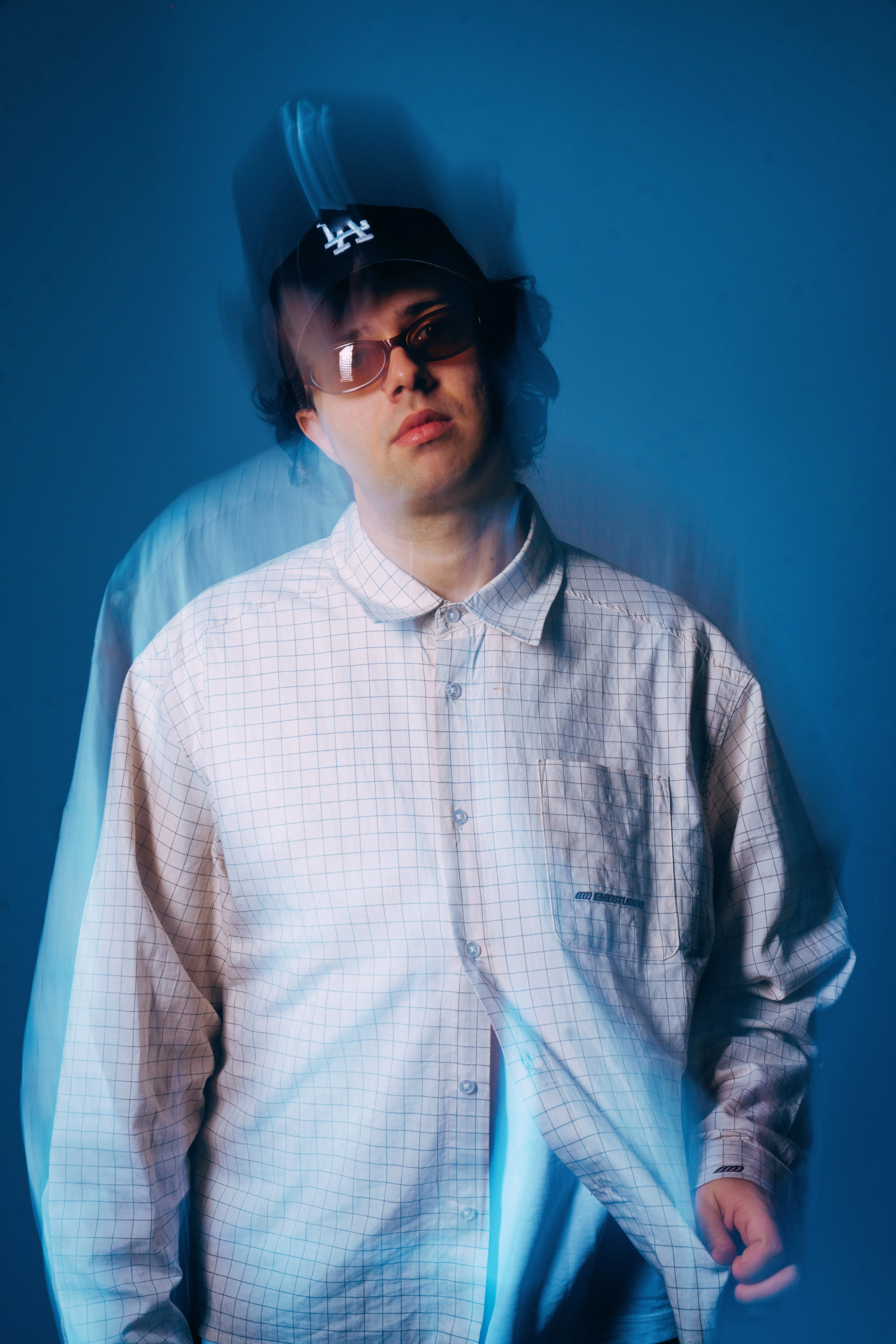 AMANN standing, motion-blurred, against a blue backdrop